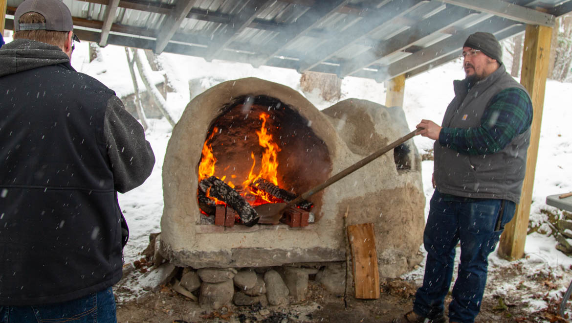 Frost Fest at Pine Lake visitors gather around open fire oven.