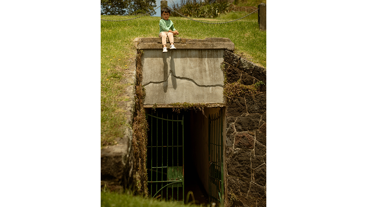 Small boy sitting on top of World War II bunker