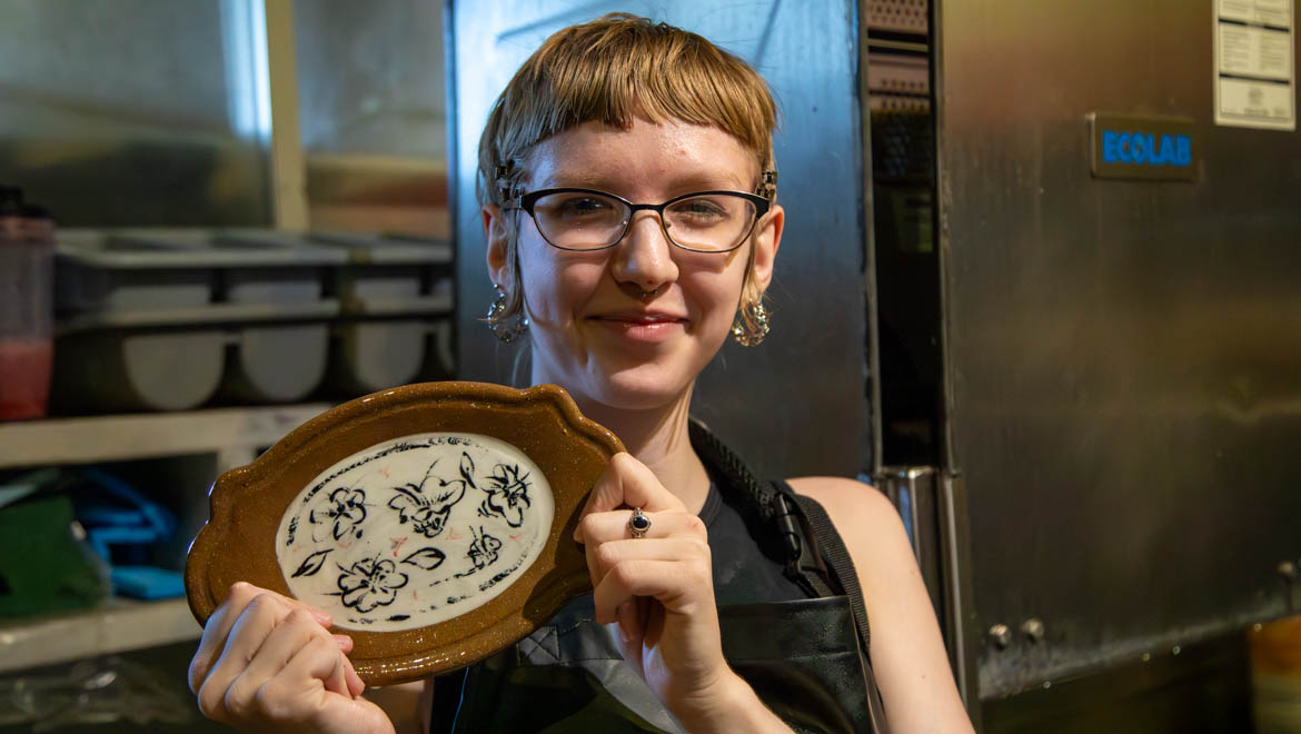 Hartwick student with finished ceramic dinnerware plate