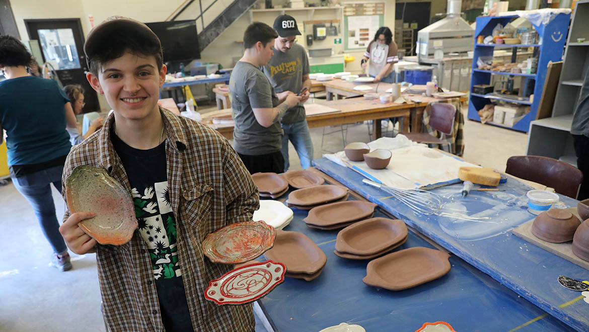 Hartwick ceramics student in ceramics studio with dinnerware