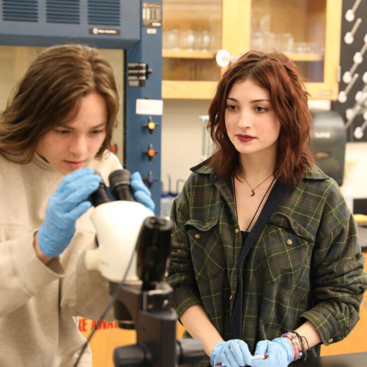 Hartwick College students in lab using microscope