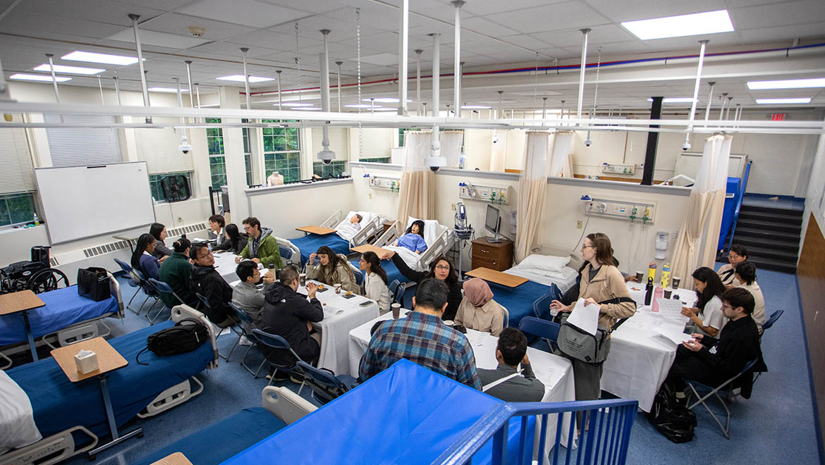 Bassett Healthcare Network professionals and resident physicians assembled at tables for debriefing in Brent R. Nicklas School of Nursing faculty simulation lab