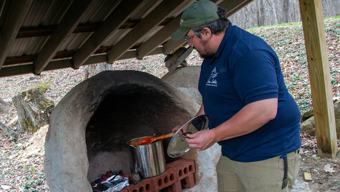 Cooking with outdoor clay oven at Hartwick College's Pine Lake
