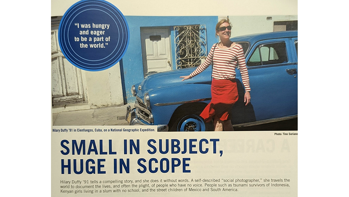 Hilary Duffy, wearing a striped shirt and red skirt, smiles while standing next to a vintage blue car in Cienfuegos, Cuba.